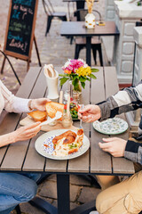 Breakfast on the summer terrace of a cafe in a European city, people, hands, action, emotions, croissant, sauce, salad, flowers, atmosphere