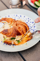 Fragrant croissant with cream cheese filling, red fish and egg, breakfast in a cozy old town on the summer terrace of an atmospheric cafe in Europe, action, hands