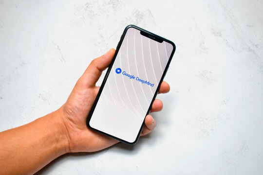 Hand holding smartphone displaying google deepmind logo on white background