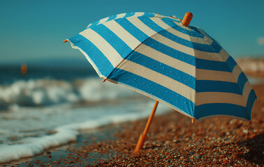 Blue And White Striped Beach Umbrella On Pebbly Shore Under Sunny Sky