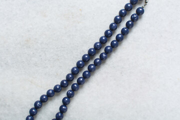 Overhead view of blue vintage necklace on marble jewelry holder, top view of vintage blue beaded necklace on a white background	
