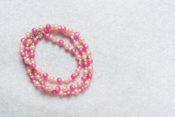 Overhead view of pink vintage necklace on marble jewelry holder, top view of vintage pink beaded necklace on a white background
