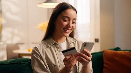 Caucasian woman happy online shopping using mobile phone kissing bank credit card smiling at home...