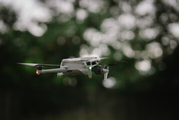 A gray drone with green lights hovers mid-air, indicating its active flight for surveillance or...