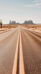 Endless desert road leading to monument valley with clear blue sky and desert vegetation