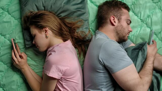 Couple Lying Together Yet Apart Focused on Their Smartphones