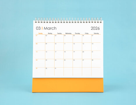 March 2026 white desk calendar on blue color background. Planning and goals concepts.