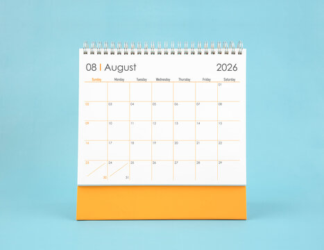 August 2026 white desk calendar on blue color background. Planning and goals concepts.