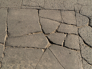 Obraz premium Close-up of cracked asphalt or concrete pavement. Urban decay texture ideal for backgrounds, construction, infrastructure, and design concepts