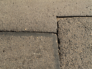 Obraz premium Close-up of asphalt pavement surface with expansion joints and textured concrete. Ideal for construction, engineering, road maintenance, and background use