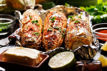 Grilled Sweetcorn with smoked paprika lime and butter in tin foil on kitchen table gluten free healthy food background
