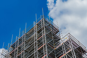 Construction scaffolding against a blue sky with clouds