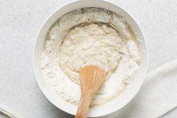 Overhead view of crackers dough being mixed in white bowl, top view of homemade crackers dough being mixed in bowl, process of making crackers