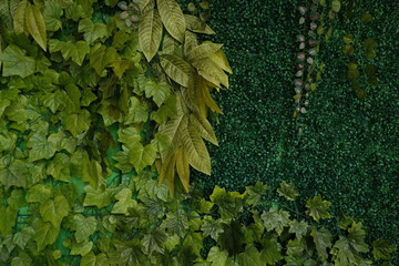 Lush green artificial foliage wall with a mix of textured ivy and tropical leaves, creating a...