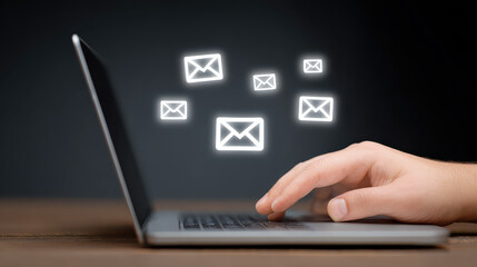 Digital Communication: A person is using a laptop with illuminated email icons floating above it, perfect for digital marketing.