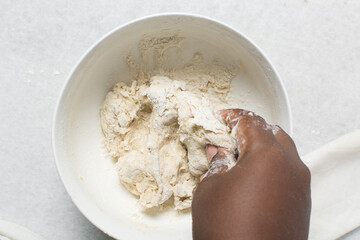 Overhead view of crackers dough being mixed in white bowl, top view of homemade crackers dough being mixed in bowl, process of making crackers