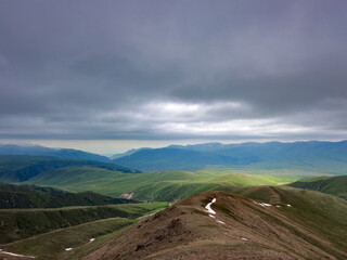 Breathtaking view of expansive green hills and mountains of Kazakhstan, Almaty under a moody,...