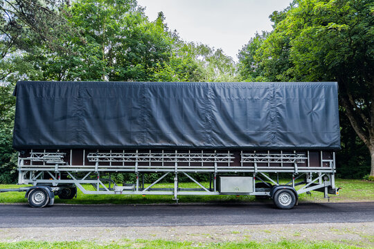 Heavy-duty trailer parked in a wooded area on a sunny day