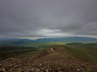 Breathtaking view of expansive green hills and mountains of Kazakhstan, Almaty under a moody,...