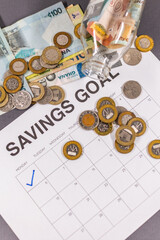 Savings goal calendar with money jar and Ghanaian Cedis notes. Symbol for personal finance, financial targets, retirement planning, and achieving long-term money goals.