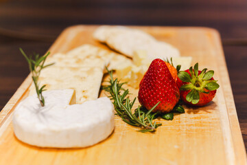 Seleted focau on strawberry with Pieces of cheese and cracker on wooden board.