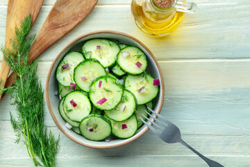 Cucumber salad with dill and red onion, overhead flat lay shot on a rustic wooden table, with...