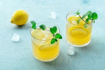 Glasses of lemonade, a mocktail with lemon juice, on a blue background, summer cold drink, with fresh mint