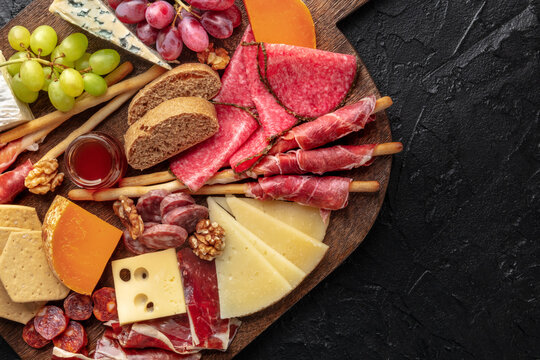 Antipasti or tapas. Charcuterie and cheese board with fruit, and bread. Cold cuts and delicatessen, top shot with copy space