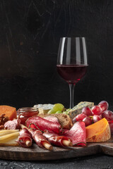 Antipasti or tapas. Charcuterie and cheese board with wine, side view with copy space. Gourmet food and drinks, delicatessen