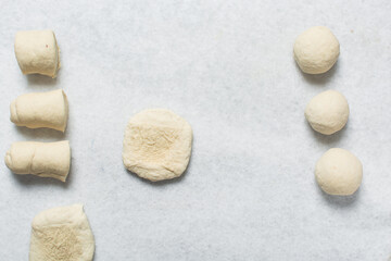 Overhead view of baozi dough being shaped over white granite countertop, top view of mantou dough being divided on granite countertop, process of making bao buns