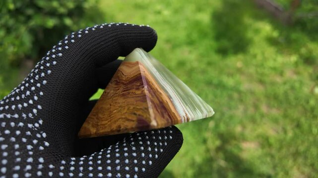 Middle-aged woman with green orgone stone pyramid. triangular stone pyramid. pyramid on the palm. stone symbol. magic item. Man showing a green orgone pyramid, close up