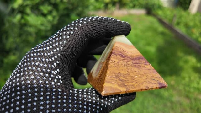 Middle-aged woman with green orgone stone pyramid. triangular stone pyramid. pyramid on the palm. stone symbol. magic item. Man showing a green orgone pyramid, close up