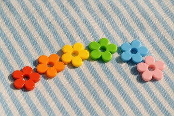 Vibrant floral-shaped plastic edging on a blue and white fabric backdrop in sunlight