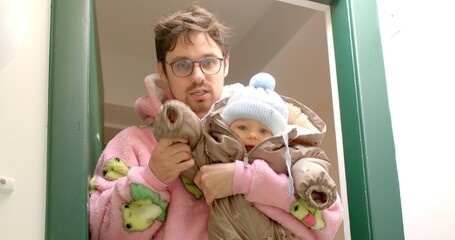 A loving parent stands in the doorway, holding a baby who is snugly wrapped in a warm and cozy...