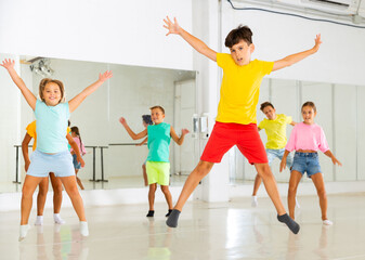 Naklejka premium Group of positive kids jumping while dancing together in studion.