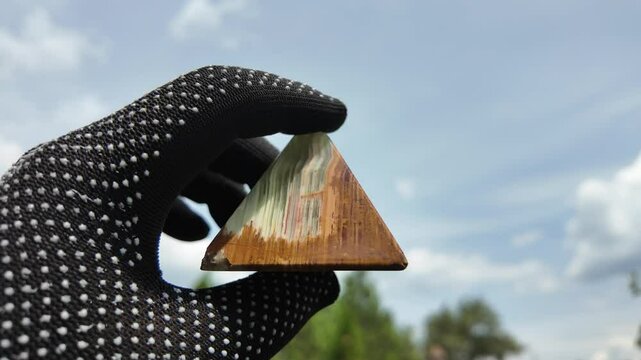 Middle-aged woman with green orgone stone pyramid. triangular stone pyramid. pyramid on the palm. stone symbol. magic item. Man showing a green orgone pyramid, close up