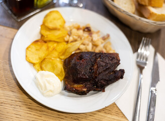 Appetizing pork cheeks baked with potatoes and beans served on platter