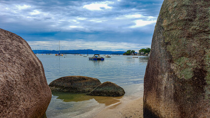 praia com pedras e barco no mar