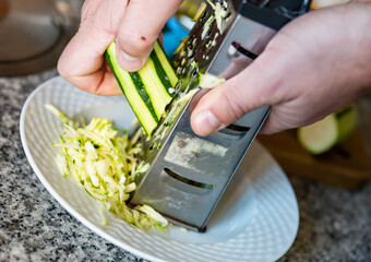Hands holding zucchini grating on grater close-up