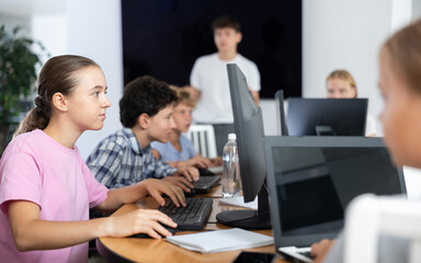 Portrait of teen schoolgirl sitting at table in computer class during lesson, smiling at camera. Concept of modern teenagers and technologies