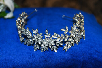 Close-up of a silver bridal tiara with crystal floral design placed on a royal blue velvet cloth....