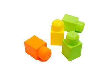 Obraz premium Toy building blocks in yellow, green, and orange scattered on a white background, representing early learning and child development.