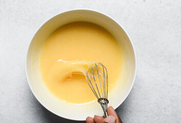 overhead view of Whisking eggs and sugar together until pale, mixing eggs and sugar by hand,...