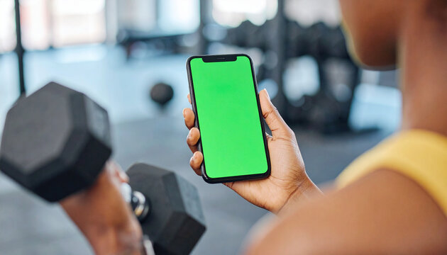 Girl hand holding a smartphone with empty green screen chromakey at the gym.
