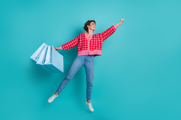 Full length photo of pretty sweet lady wear red cardigan jumping holding bargains catching emtpy...