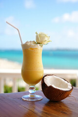 A refreshing tropical drink a pina colada on a wooden table by beach.
