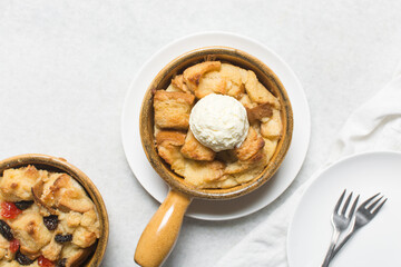 Overhead view of homemade bread pudding with raisins, top view of fresh bread pudding with raisins and cream on a white background