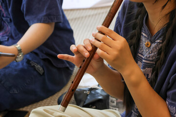 Selective focus is on the flute, a traditional Thai musical instrument made of wood.