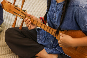 Selective focus is on a Thai musical instrument that resembles a guitar, but it's actually called a pin, a traditional Thai musical instrument made of wood.