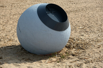 gray ball shaped trash can on sandy beach
